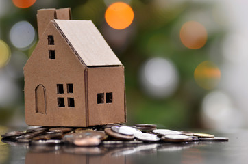 Model of house with coins on wooden table