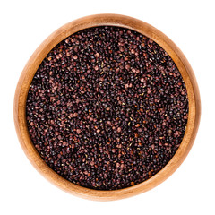 Black quinoa seeds in wooden bowl. Edible fruits of the grain crop Chenopodium quinoa in the Amaranth family is a pseudocereal and used cooked. Isolated macro food photo close up from above on white.