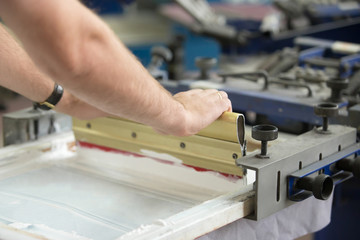 Close up of male hands exploring traditional squeegee, creating an image on white fabric clothing...