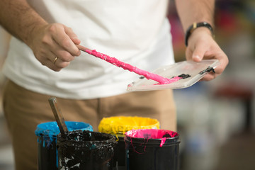 Close up of male hands at designer artwork, combining CMYK to get secondary mixture. Serigraphy...