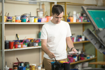 Young man combining CMYK, innovator and self employed person working at small factory printing...
