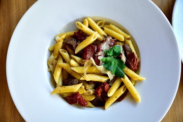 Restaurant food with fresh ingredients - pasta with dried tomatoes, parmesan and fresh rucola