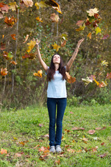 Beautiful young girl in the falling autumn leaves