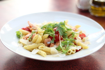 Restaurant food with fresh ingredients - pasta with dried tomatoes, parmesan and fresh rucola