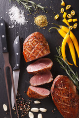 Freshly sliced roast duck breast closeup on a slate. Vertical top view