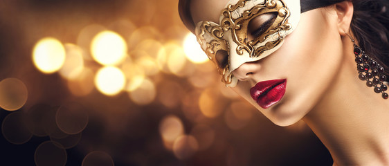 Beauty model woman wearing venetian masquerade carnival mask at party. Christmas and New Year...
