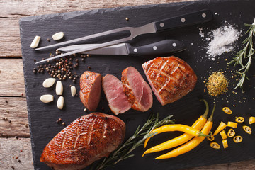 roast duck breast and ingredients close-up on a board. horizontal top view