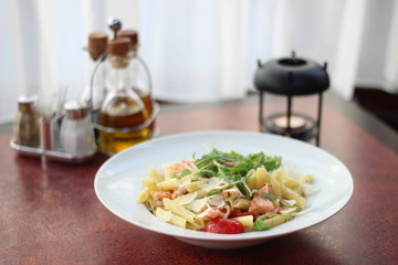 Restaurant food with fresh ingredients - pasta with dried tomatoes, parmesan and fresh rucola