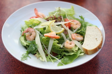 Restaurant food with fresh ingredients - salad with shrimps, parmesan and olive oil