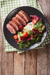 Tasty sliced roast duck breast with fresh vegetable salad close-up. vertical top view
