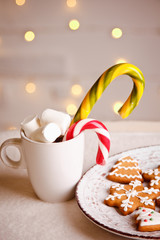 Beautiful Christmas background with gingerbread cookies on white plate with Cup of marshmallows and candy