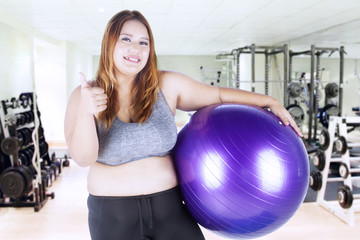 Fat woman holds purple fitness ball