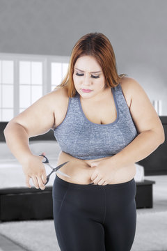 Fat woman cutting her big tummy