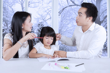 Female child studying while her parents arguing