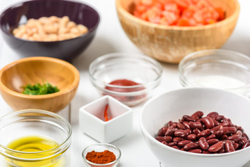 White And Red Kidney Beans, Chili Pepper, Parsley, Ketchup, Tomatoes, Olive Oil, Paprika And Yogurt Food Ingredients On White Wood Table