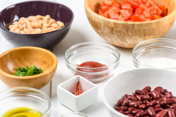 White And Red Kidney Beans, Chili Pepper, Parsley, Ketchup, Tomatoes, Olive Oil, Paprika And Yogurt Food Ingredients On White Wood Table
