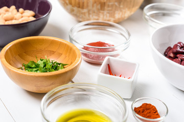 White And Red Kidney Beans, Chili Pepper, Paprika, Parsley, Olive Oil and Ketchup Food Ingredients On White Wood Table