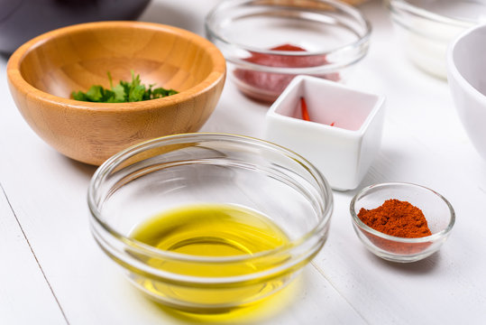 Chili Pepper, Paprika, Parsley, Olive Oil and Ketchup Food Ingredients On White Wood Table