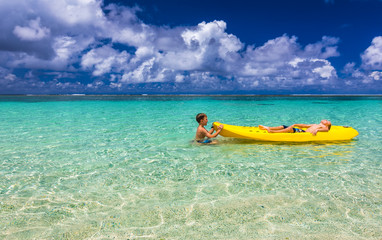 Fototapeta na wymiar Two young caucasian boys kayaking at tropical sea on yellow kaya