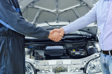 Car service. Mechanic and customer shaking hands. Excellent cooperation between car mechanic and...