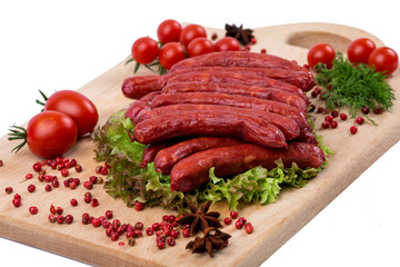 Smoked sausages on a kitchen wooden board on white background