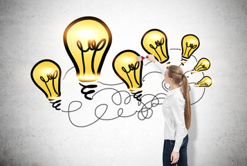 Woman with long blond ponytail drawing yellow light bulbs on a c