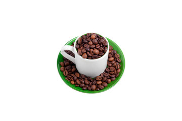 Ceramic cup on a green saucer filled with coffee beans, top view