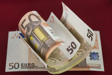 Several fifty euros banknotes on red background. Macro image. Selective focus.