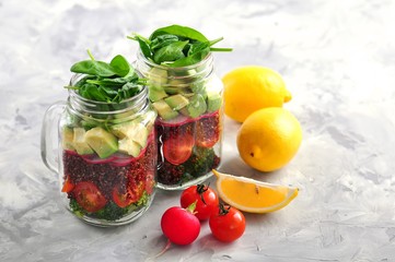 Fototapeta na wymiar Healthy salad with quinoa, avocado, tomato, red onion, baby spinach, radish and olive oil in a Mason jars.