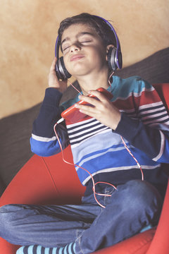 Kid enjoying the music using his smart phone and a set of headphones