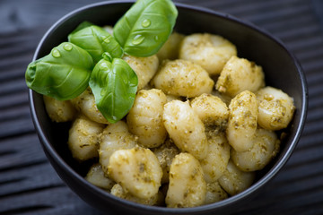 Closeup of a bowl with potato gnocchi served with basil pesto
