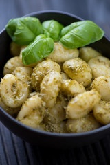 Potato gnocchi with pesto sauce and fresh basil leaves, close-up