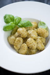 Close-up of potato gnocchi with basil pesto in a white plate