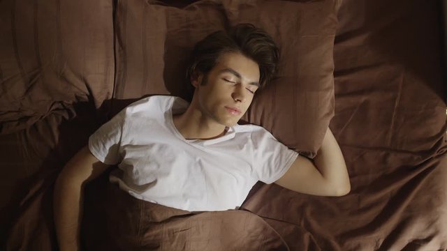 Attractive boy sleeping on a bed. Shot on RED EPIC Cinema Camera.