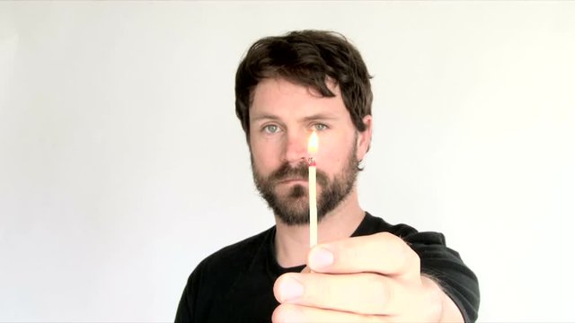 Model released man in studio lighting matchstick and blows out flame, with sound.