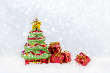 Obraz premium christmas card with tree and gifts in snow, snowflackes bokeh