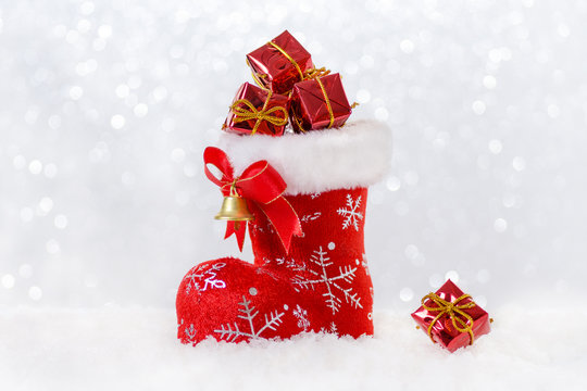 christmas stocking with gifts, santa's boot in snow, bokeh and snowflackes