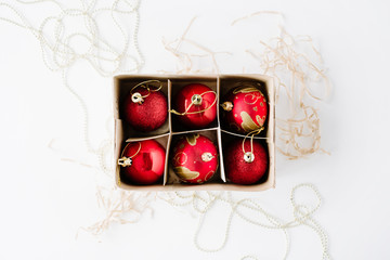 box with bright red christmas balls on white background. flat lay, top view