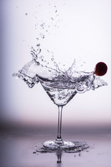 Beautiful water splash in martini glass from a cherry
