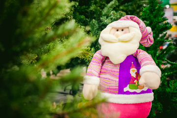 Toy santa claus near fur-trees in the store