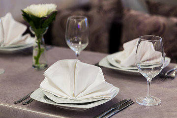 Empty glasses and dishes set in an interior new luxury restaurant with covered tables