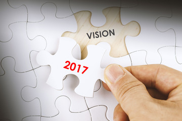 Hand holding a jigsaw puzzle with word VISION 2017.