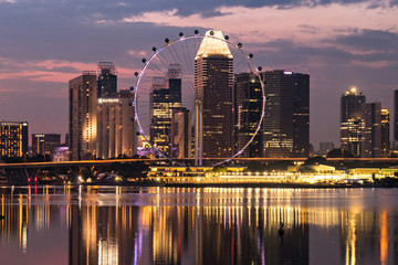 Naklejka premium Ferris wheel with office buildings reflection