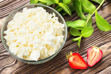 Fresh red strawberry, cottage cheese and mint, healthy breakfast in a clear plate on a wooden surface