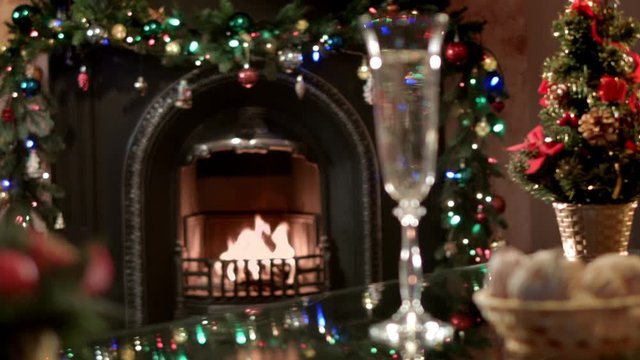 Champagne sparkle in the glass on Christmas table on a background of a burning fireplace. Beautiful festive atmosphere