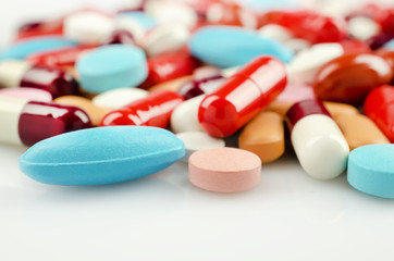 Medical theme. Multicolored Pills and Capsules on the White Surface. Closeup