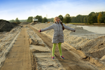 Dziewczyna, nastolatka stoi na drodze piaszczystej w kopalni żwiru.