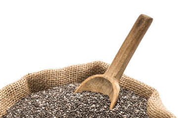 Chia seeds with a wooden spoon in a burlap sack on white background close up