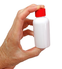 Fingers holding small white plastic bottle with red cap. Vertical.