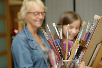 young teen girl painting with her teacher